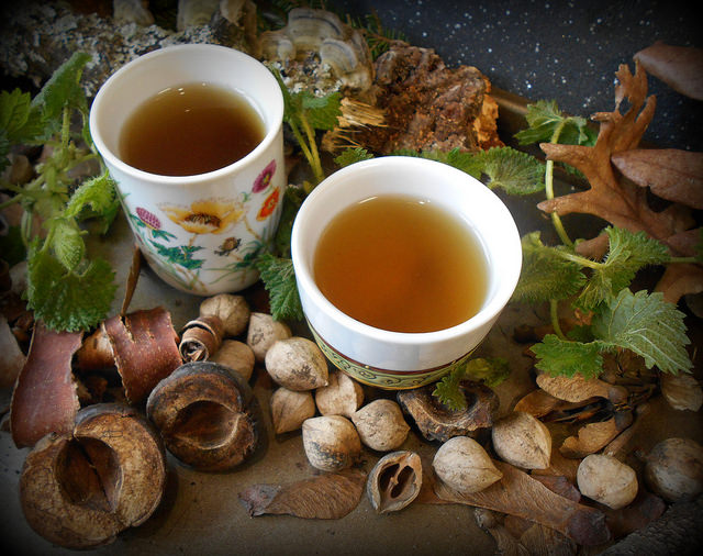 Brewed nettle tea in cups. Beautifully decorated with nettle leaves and wood.