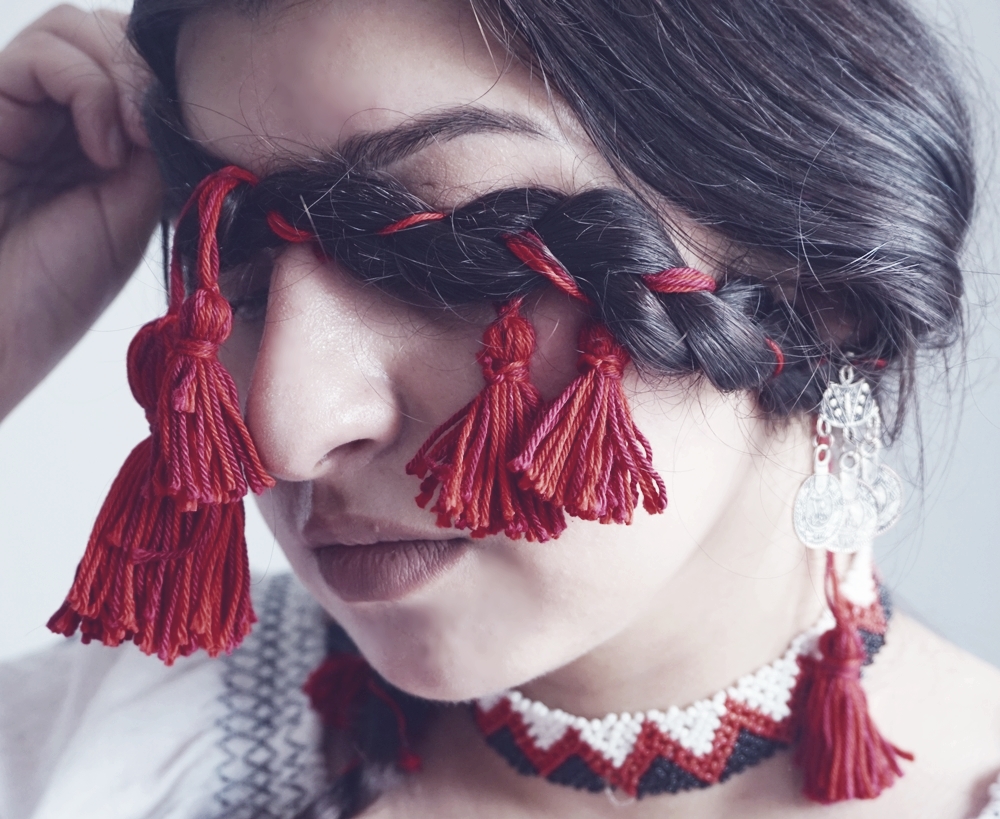 Romanian braided plaits - pigtail - with red cord. Macro on Romanian woman with national costume and traditional Romanian necklace.